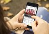 Person holding smartphone displaying fake news notification.