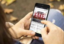 Person holding smartphone displaying fake news notification.