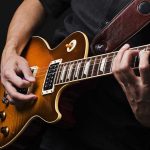 Hands playing an electric guitar