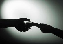 Silhouette of hands exchanging money in dim light