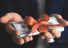 Hands holding stack of hundred-dollar bills with ribbon