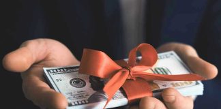 Hands holding stack of hundred-dollar bills with ribbon