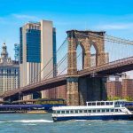 Boat passing under Brooklyn Bridge in New York