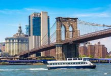 Boat passing under Brooklyn Bridge in New York