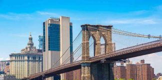 Boat passing under Brooklyn Bridge in New York