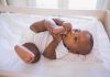 A playful baby lying in a crib, holding their feet