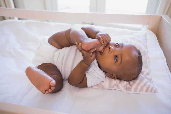 shutterstock_209676313.jpg A playful baby lying in a crib, holding their feet