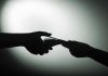 Silhouette of hands exchanging money in dim light