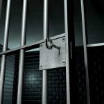 Close up of a locked prison gate with metal bars