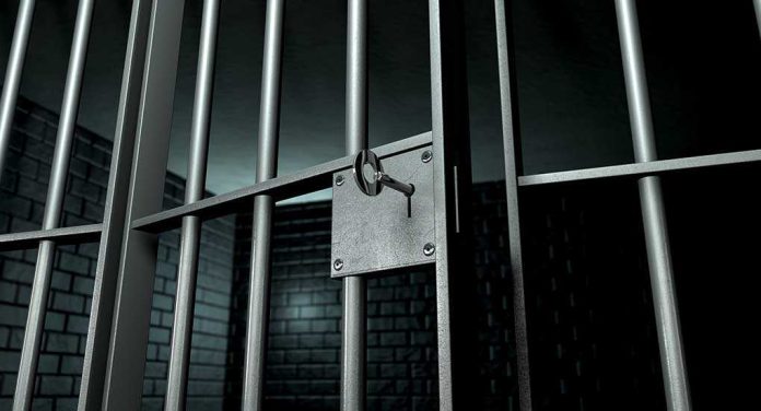 shutterstock_108487772.jpg Close up of a locked prison gate with metal bars