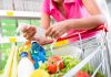 Person holding a shopping list while looking at groceries in a cart