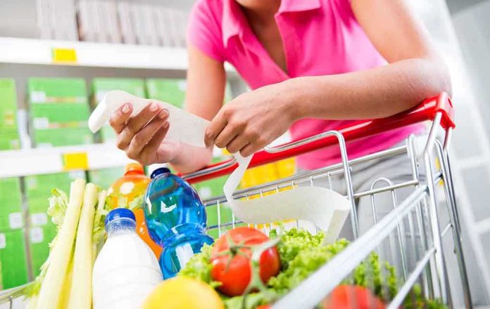 shutterstock_221704330.jpg Person holding a shopping list while looking at groceries in a cart