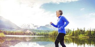 Senior woman jogging along a lakeside with mountains in the background