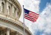 U.S. flag in front of Capitol building dome.