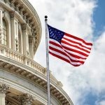 U.S. flag in front of Capitol building dome.