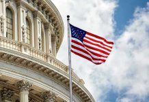 U.S. flag in front of Capitol building dome.