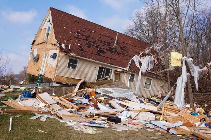 A severely damaged house tilted on its side surrounded by debris