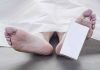 Feet of a deceased person covered by a white sheet with an identification tag