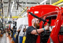 Worker assembling vehicles in a factory line.