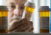 An elderly man holding a prescription bottle while examining it closely