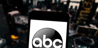 A smartphone displaying the ABC logo against an urban backdrop