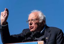 Sanders Blasts Harris—Democrats Stunned by Betrayal A speaker passionately addressing a crowd at an outdoor rally