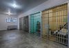 Interior view of a prison cell block with metal bars and concrete flooring