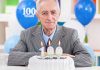 Elderly man celebrating his 100th birthday with a cake and candles