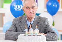 Elderly man celebrating his 100th birthday with a cake and candles