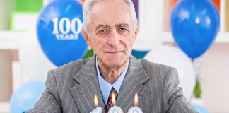 Elderly man celebrating his 100th birthday with a cake and candles