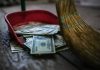 Bombshell — $8.5B on Illegals’ Healthcare vs. 300M on Law Enforcement! Broom sweeping dollar bills into red dustpan floor