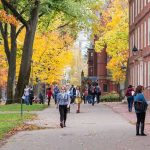University Hires Foreign Worker Instead of American Grad People walking on a college campus in autumn.
