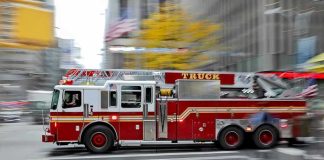Red fire truck driving through city street crosswalk