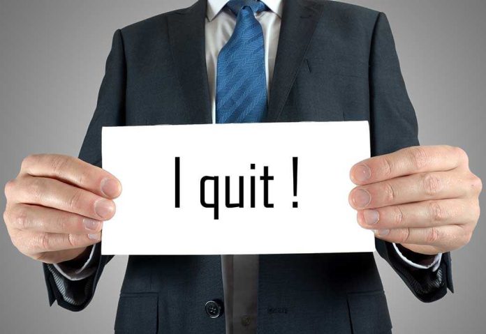 shutterstock_195128024.jpg A man in a suit holding a sign that says I quit!