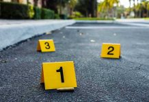 Crime scene markers on asphalt with bullet casing.