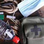 An assortment of emergency supplies including a first aid kit, water bottle, face mask, and matches