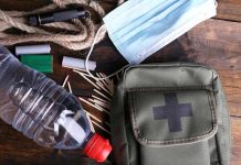 An assortment of emergency supplies including a first aid kit, water bottle, face mask, and matches
