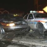 A damaged car and a police vehicle involved in a nighttime accident