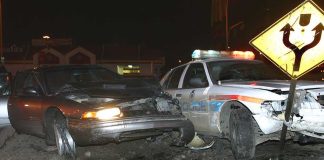 A damaged car and a police vehicle involved in a nighttime accident