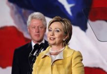 Shock Emails Reveal Epstein’s Direct Access to Power Hillary Clinton delivering a speech with Bill Clinton in the background