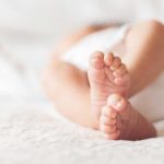 Mom SELLS Baby for Beer! Close-up of baby feet lying on blanket.