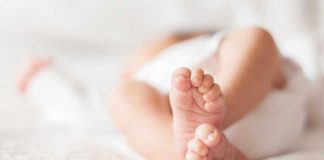 Mom SELLS Baby for Beer! Close-up of baby feet lying on blanket.