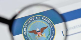 Magnifying glass over Department of Defense logo.