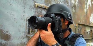 Person in helmet taking photos with a large camera.