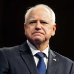 Feds GIVE WALZ Deadline in Explosive Fraud Probe Man in suit with a U.S. flag pin.