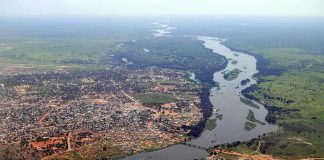 Aerial view of a river winding through a town and green fields
