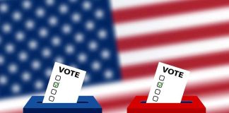 Ballots in boxes with American flag background.