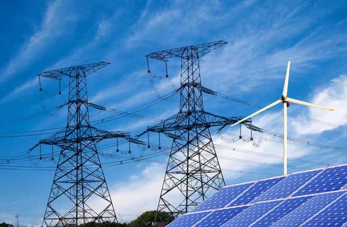 138865700 Power lines, solar panels, and wind turbine against sky.