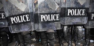 Police officers in riot gear holding shields.