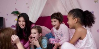 Group of children laughing and enjoying a sleepover in a cozy bedroom